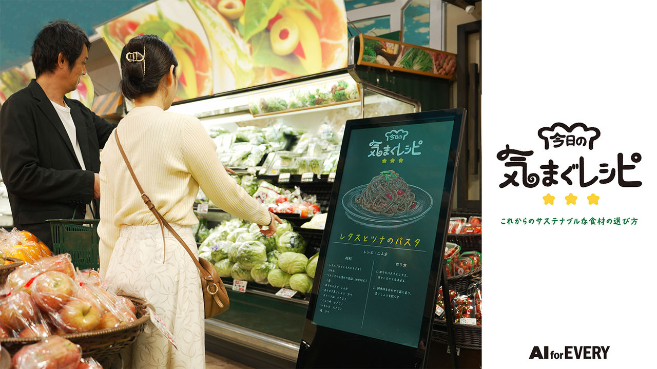 拡大画像：「今日の気まぐレシピ」のサービスイメージです。スーパーで野菜を選んでいる男女の横にサイネージが設置されており、レシピが提案されている様子を表しています。