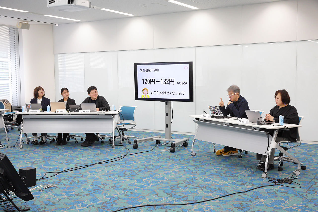 座談会で登壇者5名が話している写真：  向かって左側に3名、あかねさん、ミーさん、Tenさんが座っており、スライドを表示するモニタを挟んで、向かって右側には植木氏、千葉が座っている。