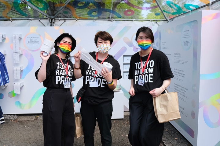 イメージカラーであるレインボーのマスクと、TOKYO RAINBOW PRIDEの白い文字が印刷された黒いTシャツを着たボランティア3人