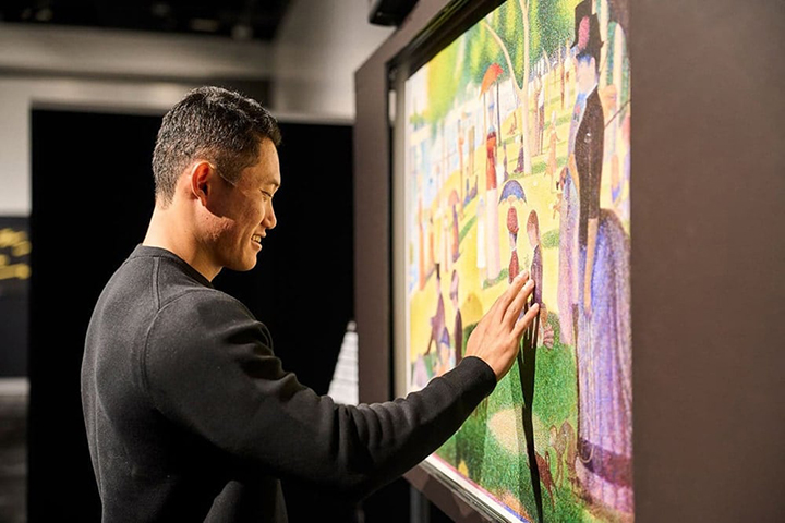 写真：「グランド・ジャット島の日曜日の午後」の点描の凹凸に触れて微笑む若生選手